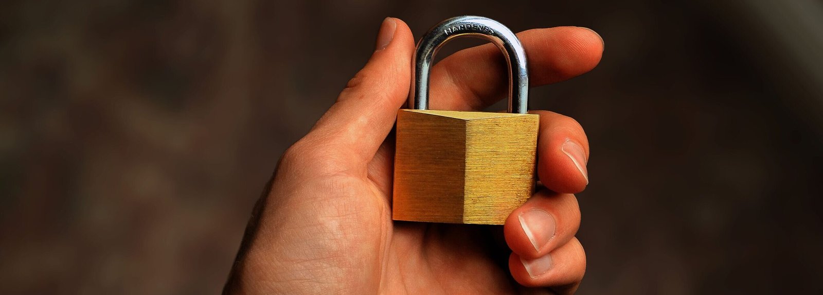 Hand holding a brass padlock, symbolizing security and protection