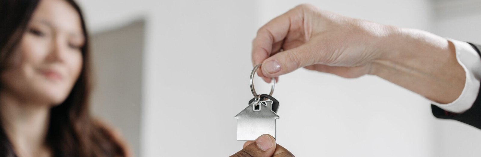 Close-up of a professional handing over a house key to a client inside a new home.
